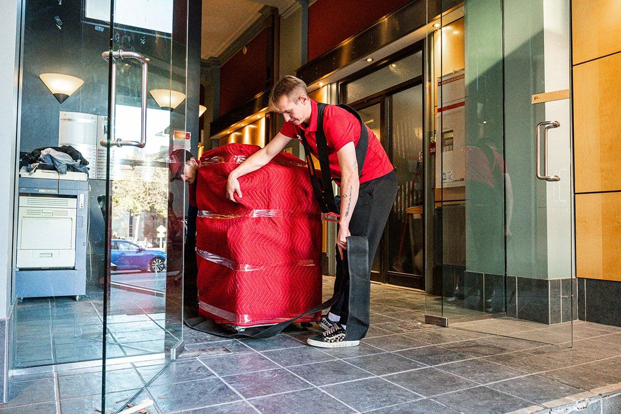 Déménageur transportant un meuble volumineux emballé à travers une entrée étroite